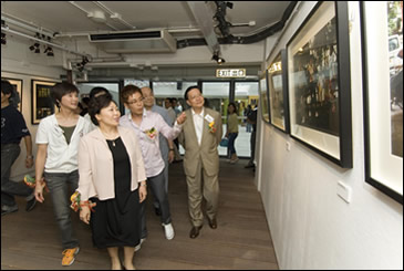 相片：攝影師謝至德(左三)向嘉賓介紹其攝於蘇屋邨的作品。