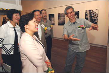 相片：攝影師黃勤帶(右一)向嘉賓介紹其攝於石硤尾邨的作品。