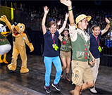 相片：迪士尼樂園朋友陪同同樂會會長應耀康(中) (左圖)、主席何樂素芬(左) (右圖)和管理層同事，在開幕典禮進場儀式與現場朋友揮手。