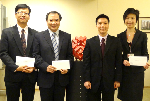 相片：晋升为高级屋宇保养测量师的霍伟华(左一)、陈启霖(左二)和卢颖妍(右一)，获副署长(屋邨管理)李国荣颁授升职贺函。