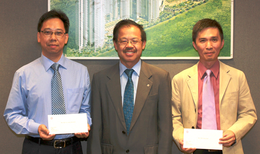 相片：晉升為高級屋宇裝備督察的葉子文(左)和朱健民(右)，獲助理署長(工務)(二)張建強頒授升職賀函。