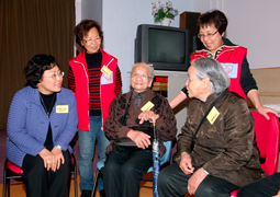 Photo: Ms. Eva CHENG (Chairman of HA) chats with the elderly and enjoys pastries prepared by the elderly in the visit