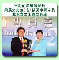 相片: 当时的房屋署署长梁展文先生(左)接受申诉专员戴婉莹女士颁发奖座